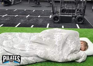 Pilates instructor sleeping on gym floor with duvet